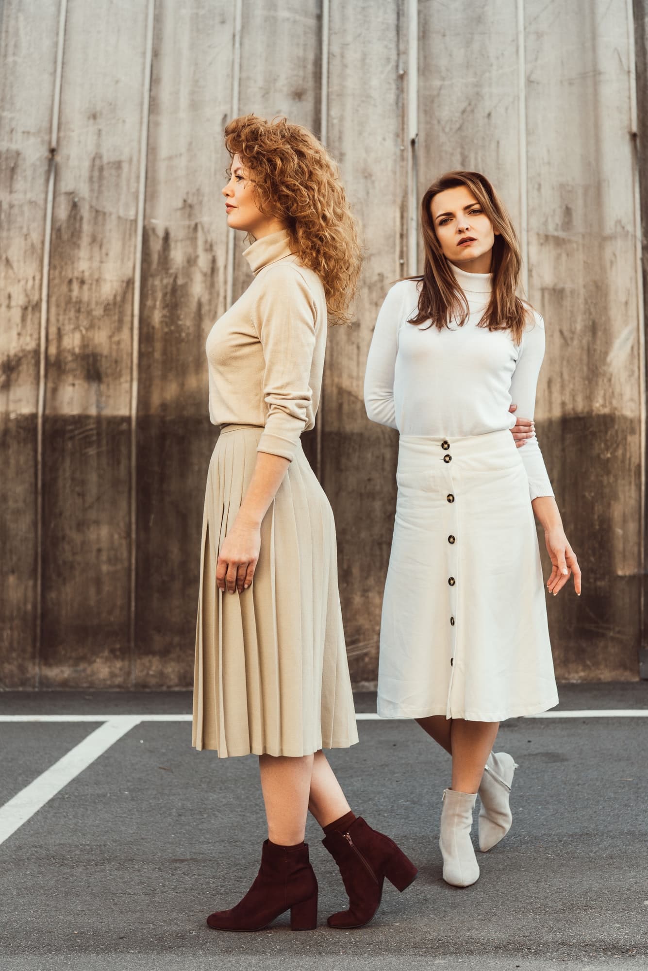 fashionable female models in turtle necks and skirts posing at urban street